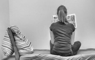 A girl on bed holding a book in her hands & read it