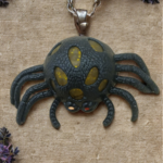 A black spider-shaped stress toy with yellow glitter gel popping through its textured body on a crinkled fabric background.