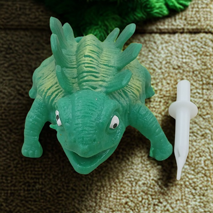A textured green ankylosaurus dinosaur stress toy with ridges on its back sitting on an office desk setup.