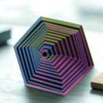 A vibrant hexagonal stress prism with tiered ridges in green, blue, and purple sitting on a professional office desk.