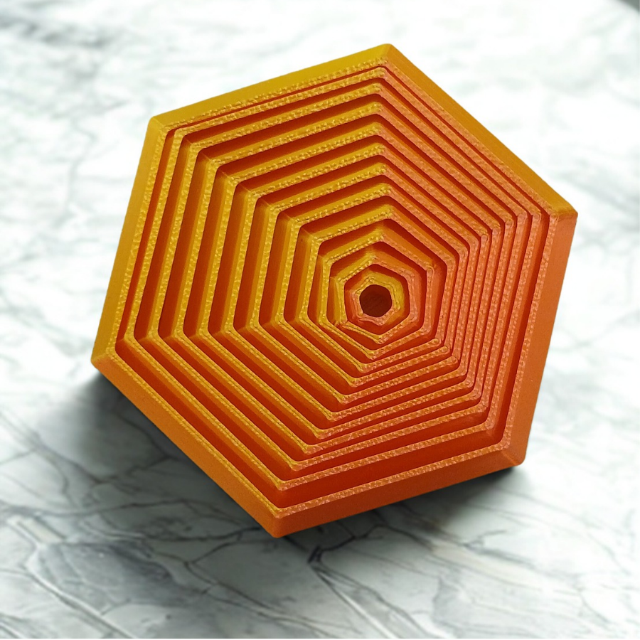 A vibrant hexagonal stress prism with tiered ridges in green, blue, and purple sitting on a professional office desk.