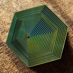 3D layered hexagonal geometric sculpture in green and teal gradient, top-down view on a textured brown background, focus tool for meditation.