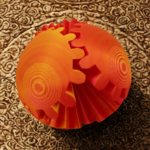 A 3D-printed spherical gear toy with orange and red gradient gears interlocking on a light wooden surface.