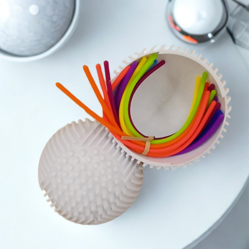 Top-down view of colorful silicone stretch strings coiled inside a light-grey textured tactile sensory sphere.